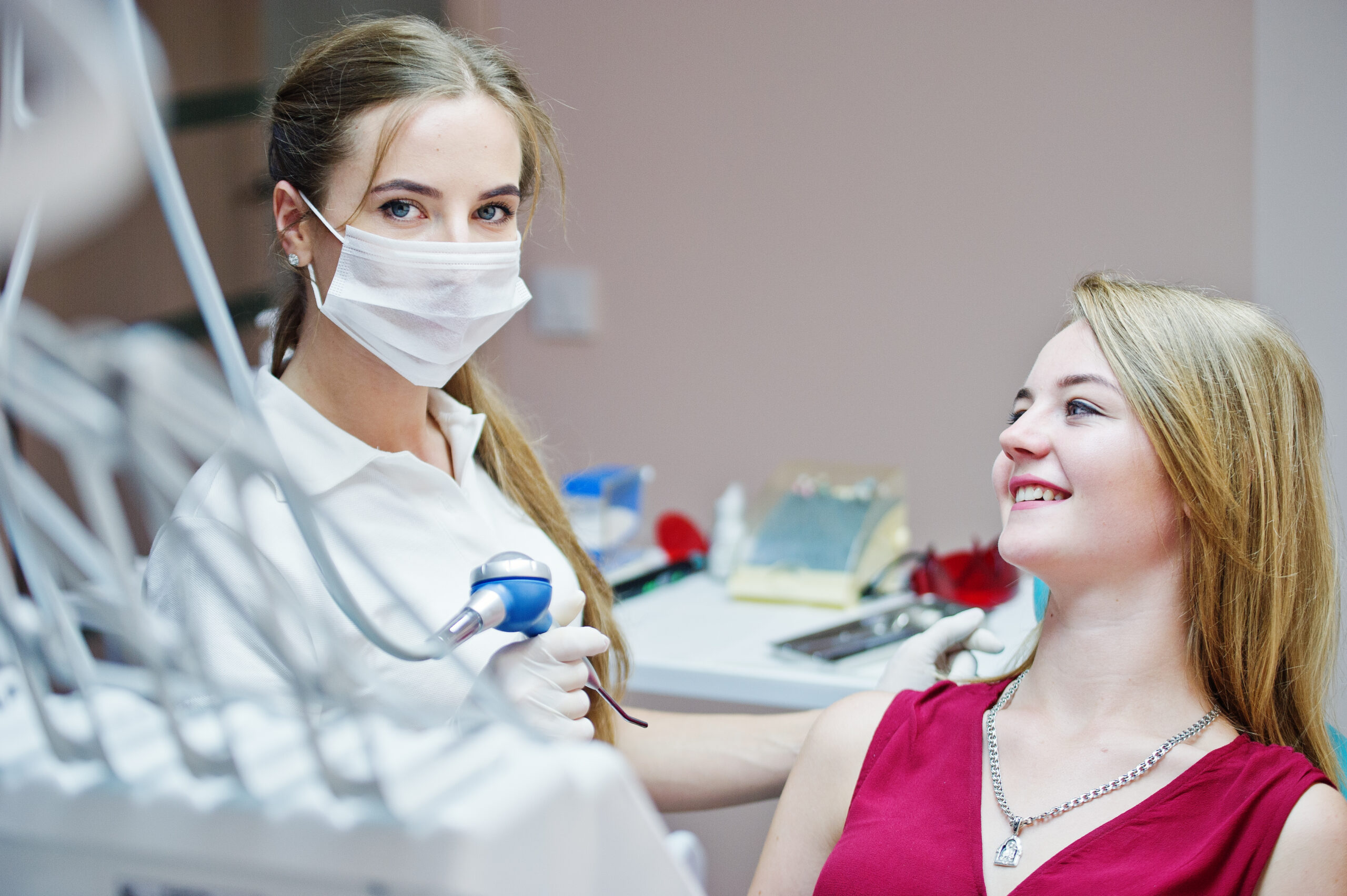 attractive patient in red violet dress laying on the dental chai