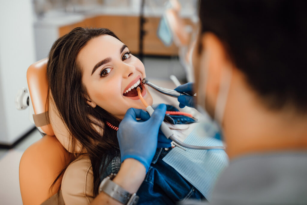 Dentist examining a patient’s teeth with advanced dental equipment in a modern clinic